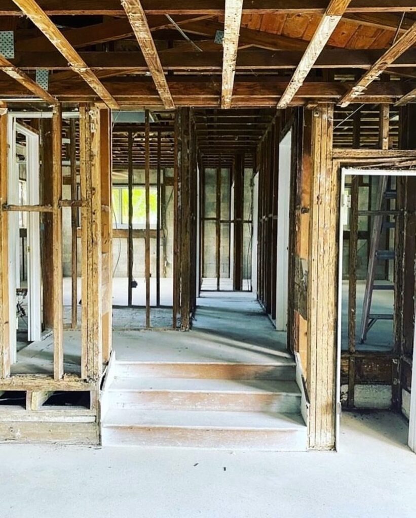 Home stripped to the framing during an interior demolition, with walls, ceilings, and finishes removed and the original structure left standing.